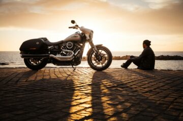 Ein Motorrad steht bei Sonnenuntergang am Meer, während ein Mann daneben sitzt – erfahren Sie, wie Sie Motorräder inserieren und ansprechende Verkaufsanzeigen gestalten können.