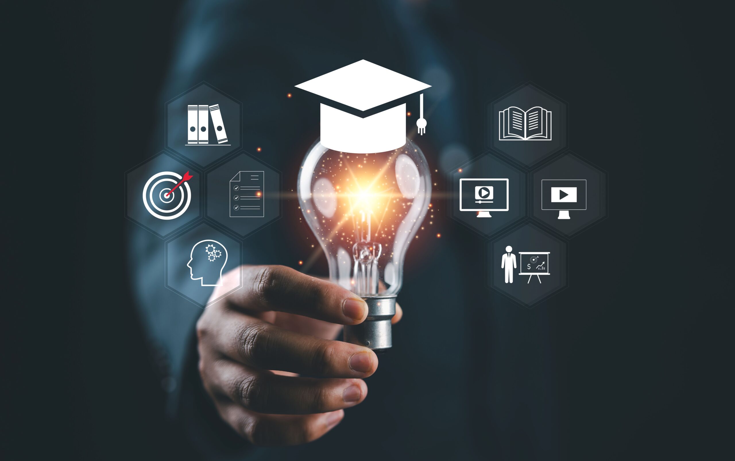 Hand hält leuchtende Glühbirne mit Absolventenhut – Symbol für Erkenntnis durch Compliance E-Learning
