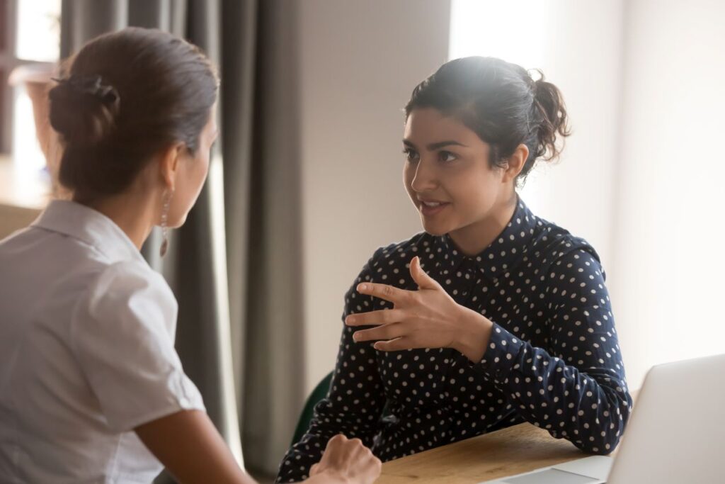 Zwei Frauen sitzen im Einzelcoaching und sprechen ueber Argumentationsstrategien aus einem Verhandlungstraining
