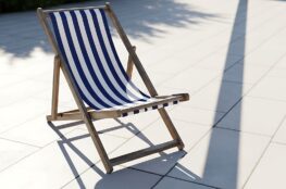 Gestreifter Liegestuhl auf heller Terrasse im Sonnenlicht – Symbolbild fuer Garteninspiration