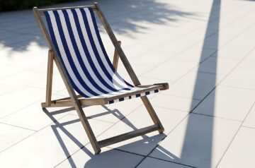 Gestreifter Liegestuhl auf heller Terrasse im Sonnenlicht – Symbolbild fuer Garteninspiration