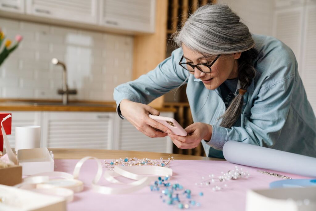 Aeltere Frau fotografiert selbst arrangierten Schmuck mit dem Smartphone – Geschenkidee mit Bedeutung – thomas sabo